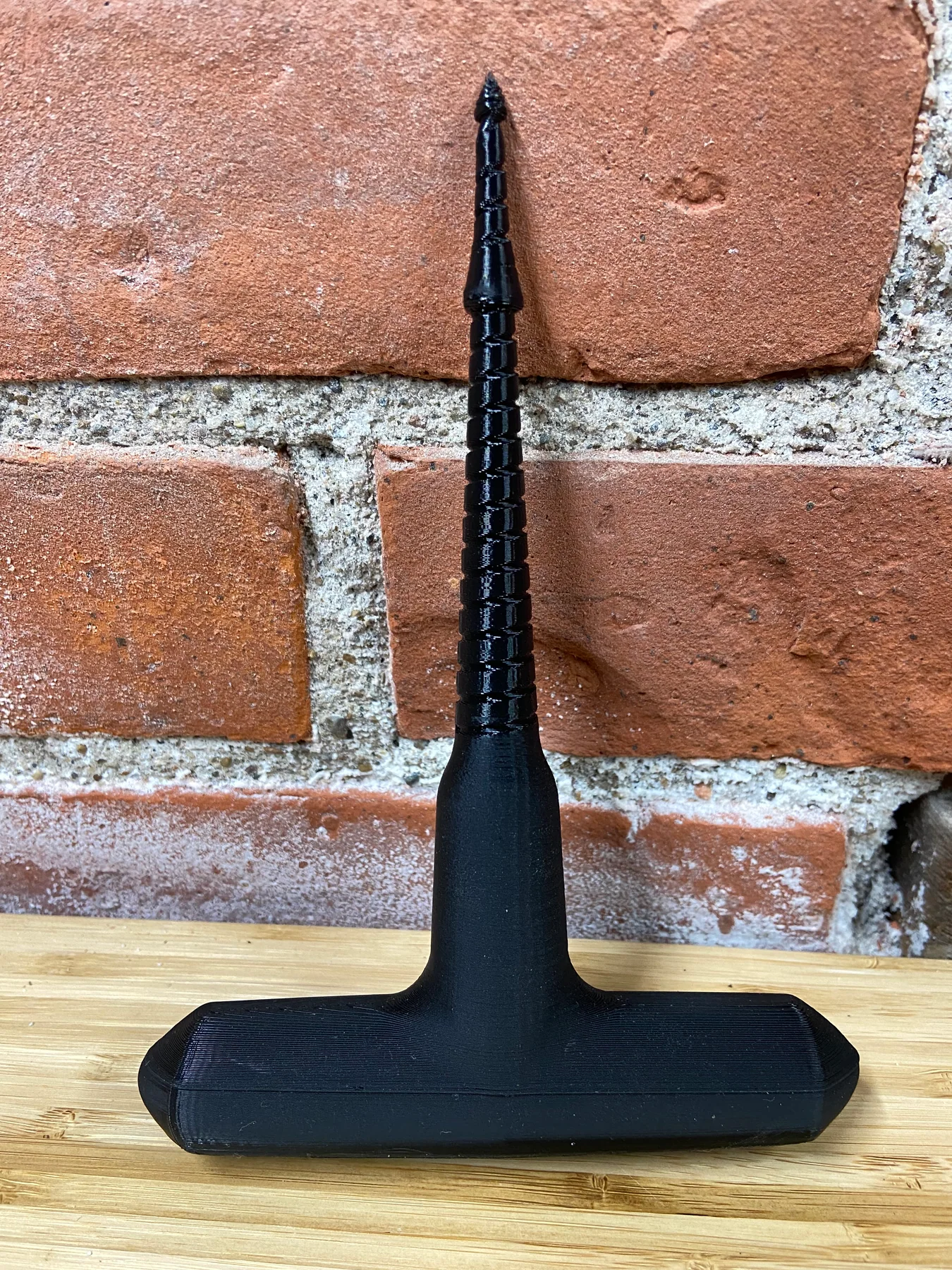 Black 3D-printed T-handle tool with a threaded tapered shaft, standing upright