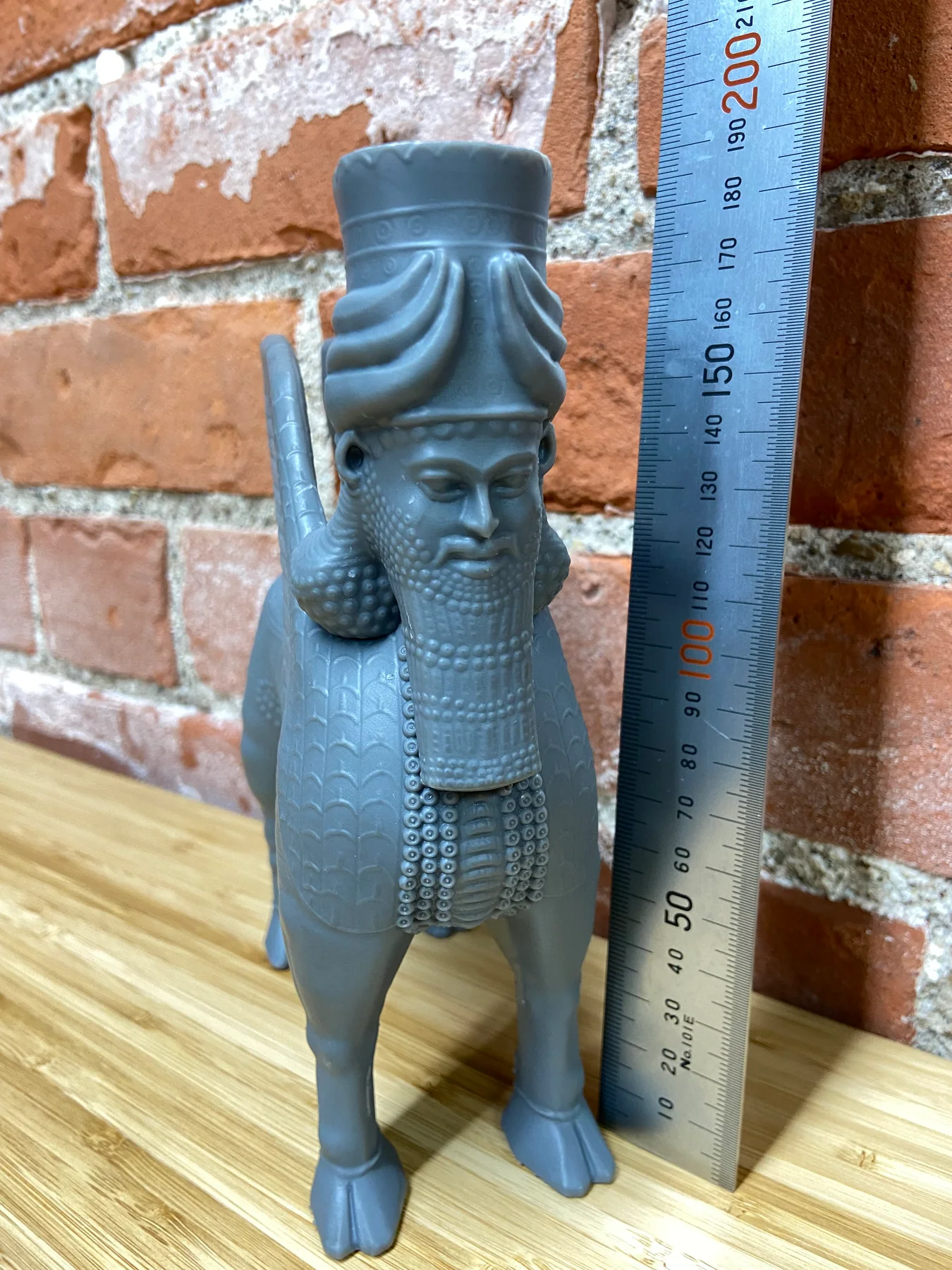 Gray resin 3D print of an Assyrian lamassu statue beside a 200 mm ruler